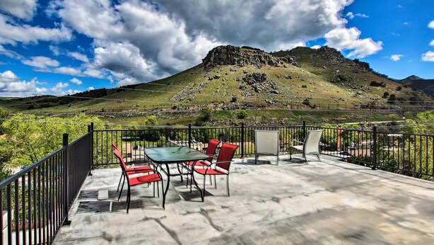 Une terrasse extérieure avec une table et des chaises, offrant une vue sur un paysage montagneux.