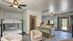 Une chambre avec des lits superposés, un bureau, une chaise et un ventilateur de plafond.