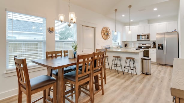 A modern kitchen with white cabinets, stainless steel appliances, and a wooden dining table with chairs. - Cozy Rockport Vacation Rental Near Fishing! (Rockport)