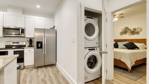 A compact kitchen with a microwave, stove, and refrigerator. A washing machine is visible through an open door. - Cozy Rockport Vacation Rental Near Fishing! (Rockport)