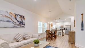 A spacious living area with a sofa, coffee table, and a dining table with chairs. There is a kitchen in the background with modern appliances. - Cozy Rockport Vacation Rental Near Fishing! (Rockport)