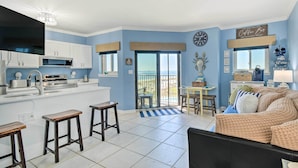 Una cocina moderna con armarios blancos, una isla grande y un comedor con vistas al océano.
