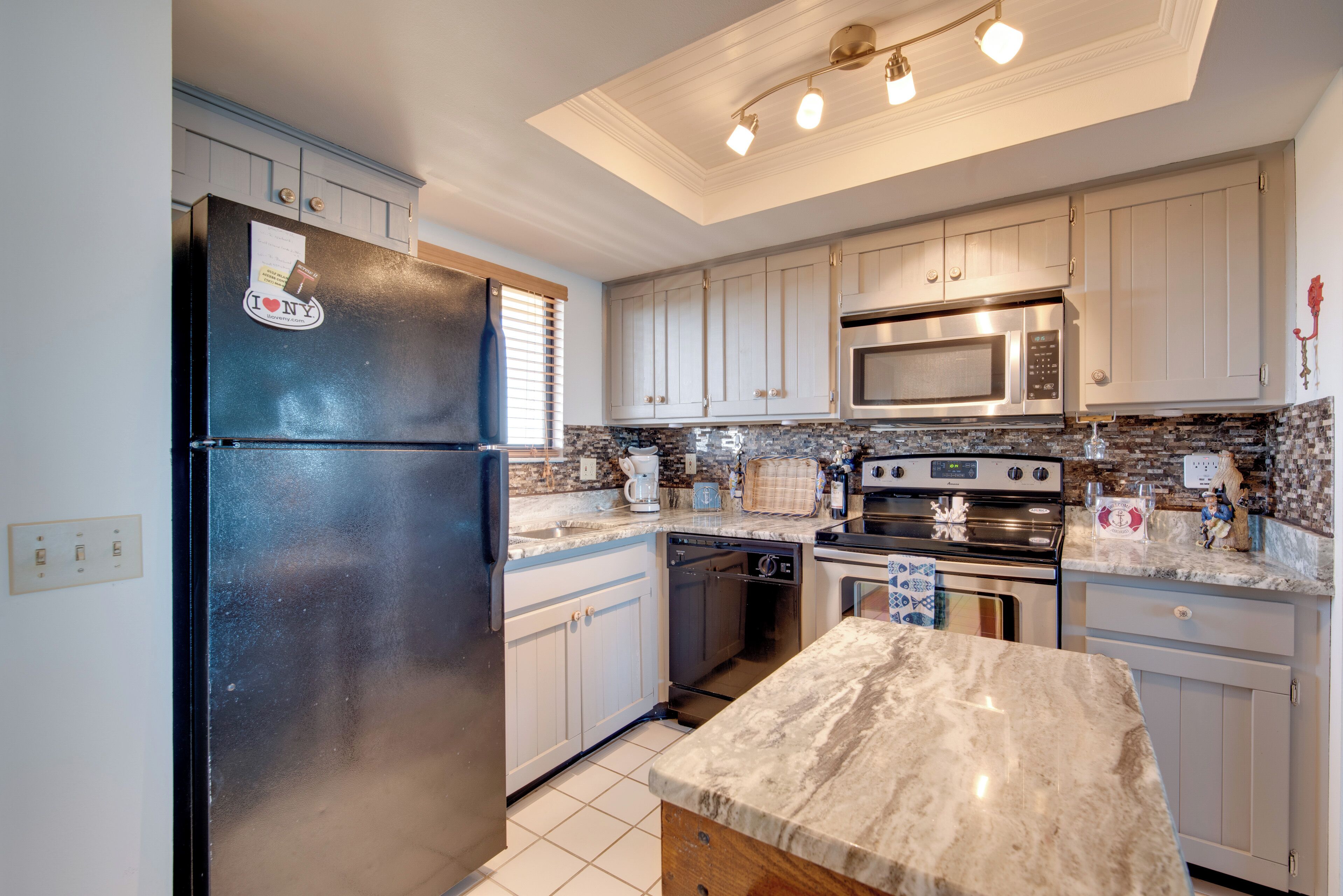 A kitchen with white cabinets, a black refrigerator, a microwave, an oven, and a dishwasher.