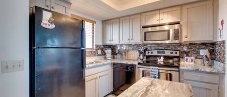 A kitchen with white cabinets, a black refrigerator, a microwave, an oven, and a dishwasher.