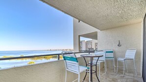 A balcony with a view of the sea, white metal chairs, and a small round table. - Gulf-front Views: Coastal Hudson Condo! (Hudson)
