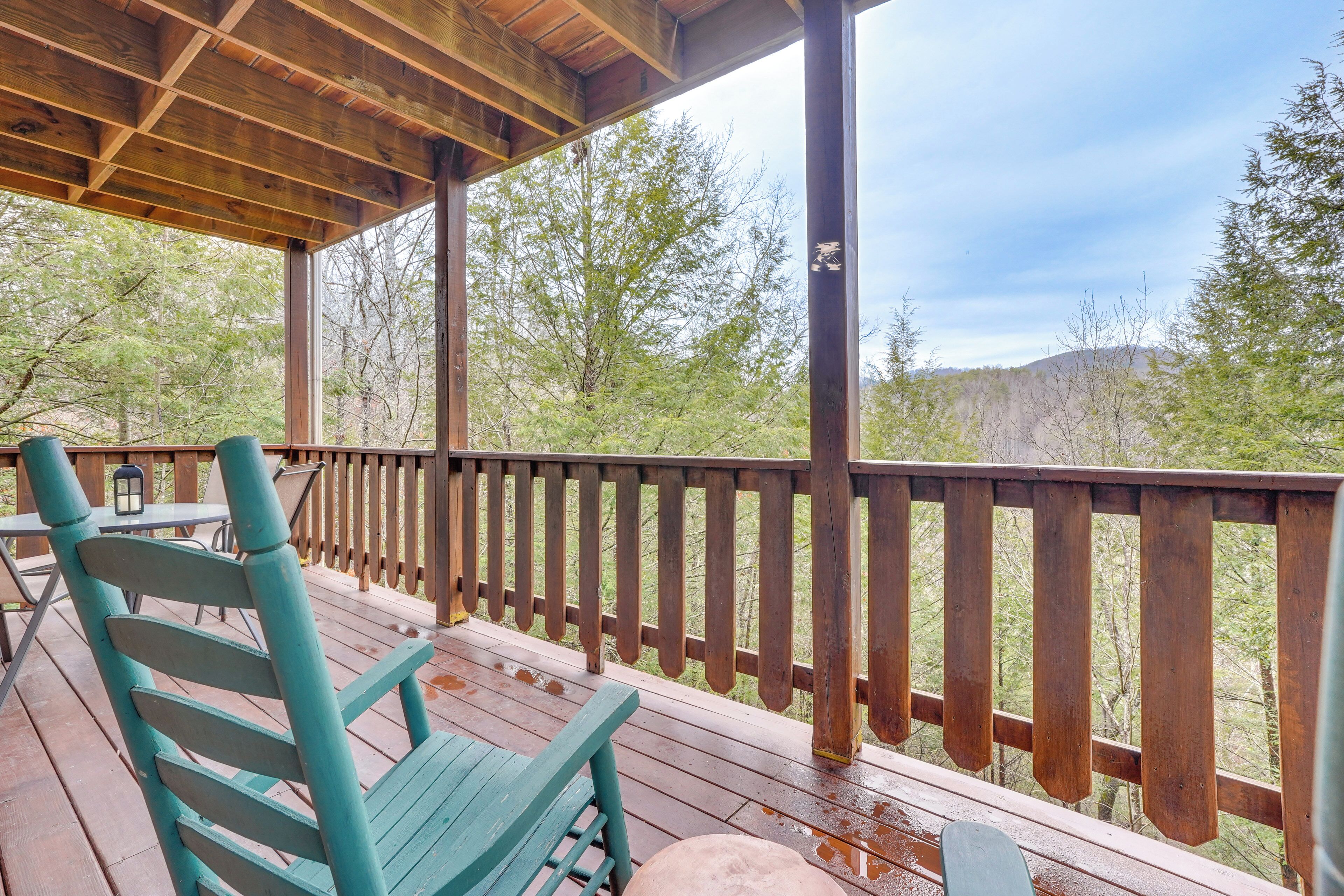 A wooden deck with a railing, a green chair, and a table.
