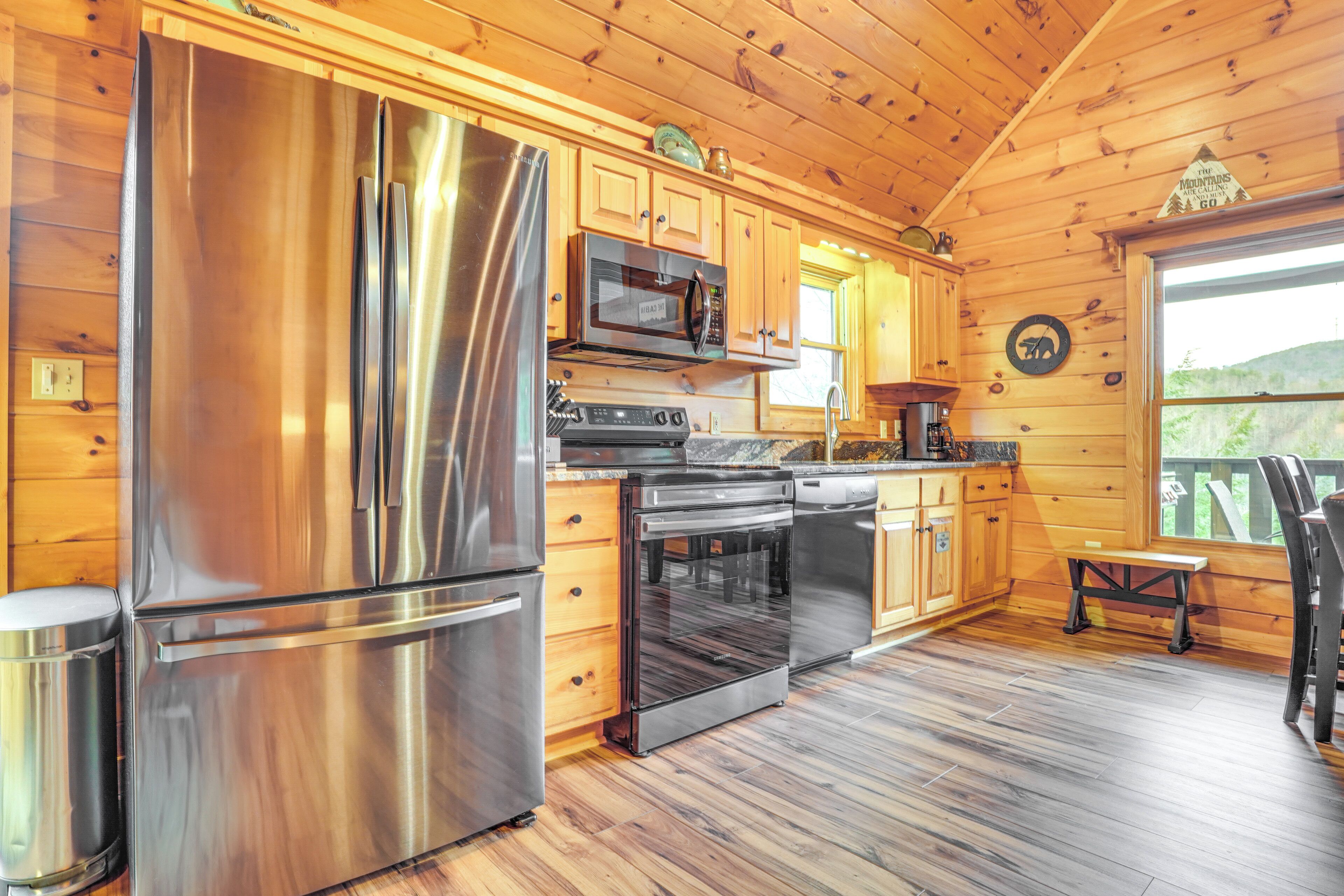 A modern kitchen with stainless steel appliances, wooden cabinets, and a view of the outdoors.