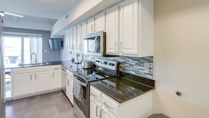 A modern kitchen with white cabinets, stainless steel appliances, and a granite countertop. - Waterfront Middle Bass Condo w/ Lake Erie Views! (Put-in-Bay)