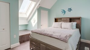 A bedroom with a bed, a skylight, a window, a door, and a wall decoration. - Waterfront Middle Bass Condo w/ Lake Erie Views! (Put-in-Bay)