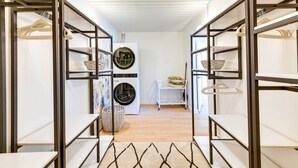 Une buanderie équipée d’étagères métalliques, d’un lave-linge et d’un étendoir.