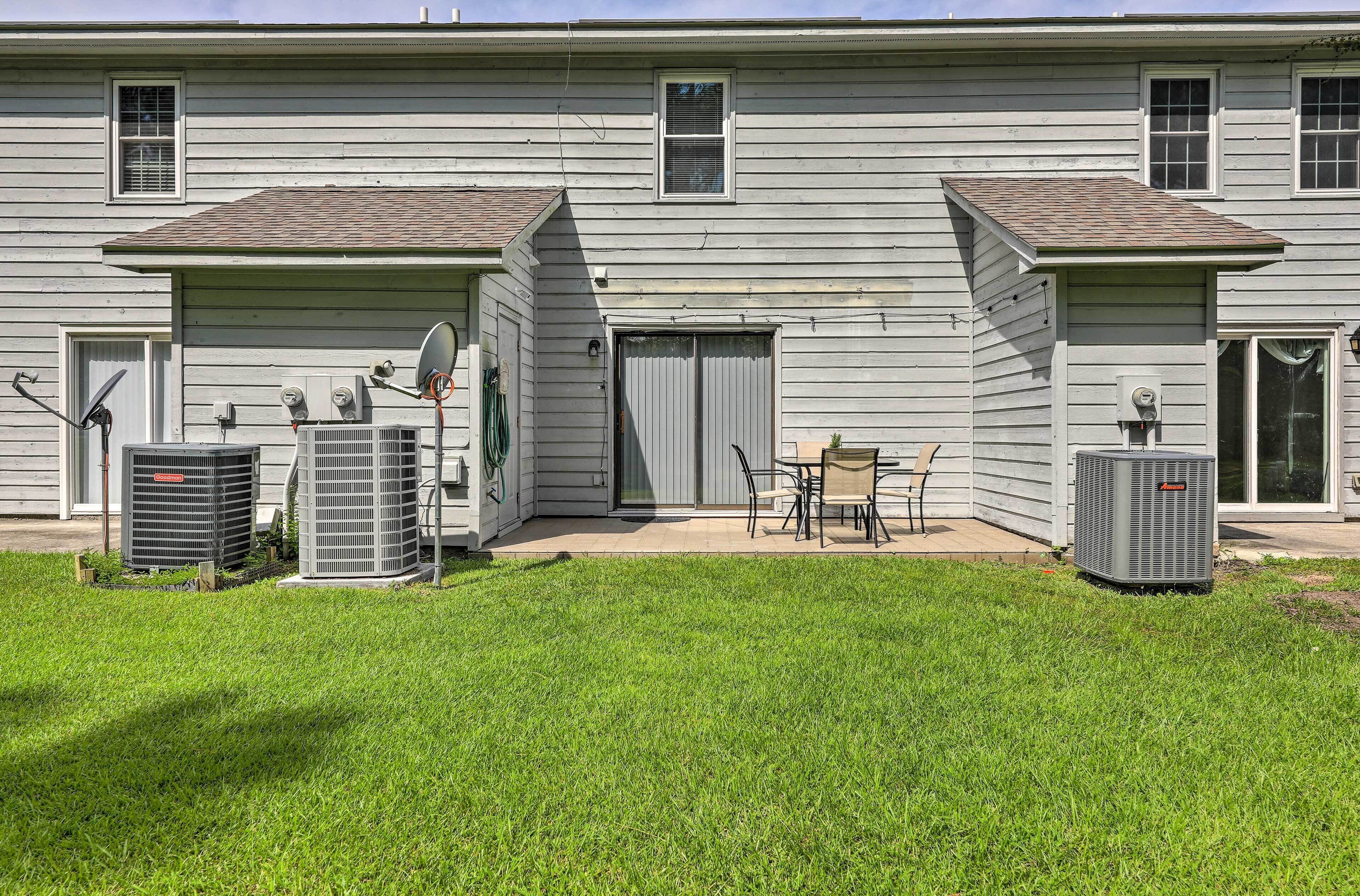 A two-story building with a flat roof, satellite dish, and two air conditioning units in the yard.