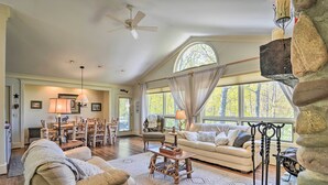 A spacious living room with a large window, a fireplace, and a stone wall. - Resort-style Harbor Springs Home Near Ski Resort! (Harbor Springs)
