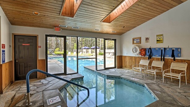 A pool area with a wooden ceiling, stone flooring, and a view of the outdoors. - Resort-style Harbor Springs Home Near Ski Resort! (Harbor Springs)