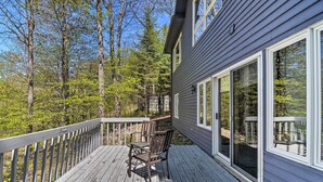 A wooden deck with a table and chairs, overlooking a forested area. - Resort-style Harbor Springs Home Near Ski Resort! (Harbor Springs)