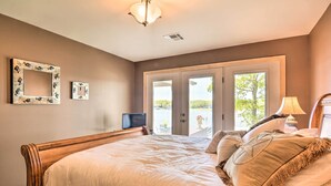 Un dormitorio con una cama grande, televisión y puerta que da a un balcón.
