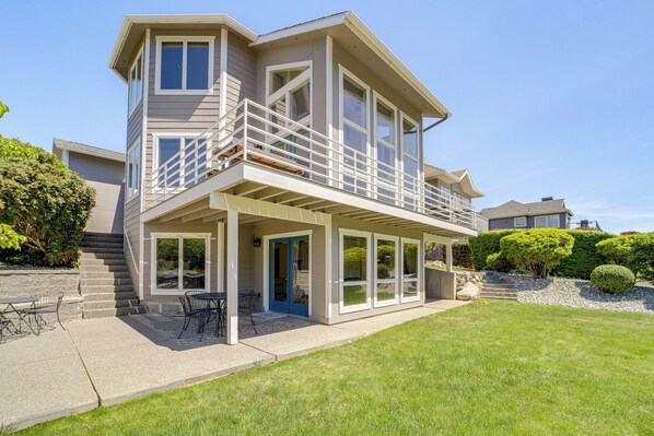 A two-story house with a balcony, a covered patio, and a well-maintained lawn. - Modern Retreat w/ Hot Tub - Steps to Lake Chelan! (Manson)
