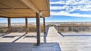 A wooden boardwalk leading to a covered area with benches and a railing, overlooking a beach. - Oak Island Beachfront Condo w/ Community Pool (Oak Island)