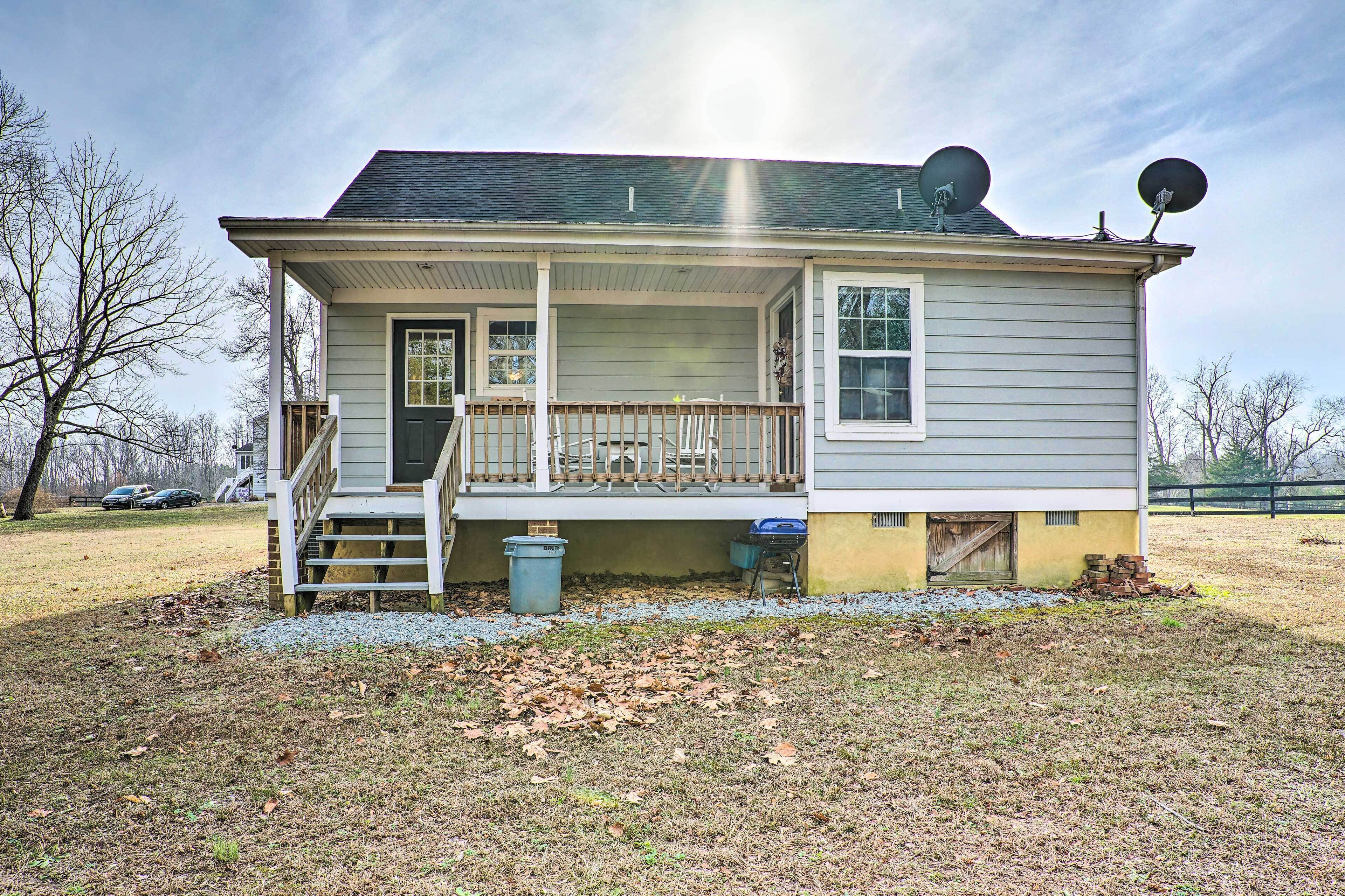 A two-story house with a front porch, a small staircase, and satellite dishes on the roof.