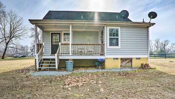 A two-story house with a front porch, a small staircase, and satellite dishes on the roof.