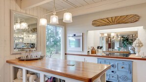 A kitchen with a wooden countertop, white cabinetry, and a large mirror.