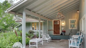 A covered porch with white wooden benches and a wooden door.
