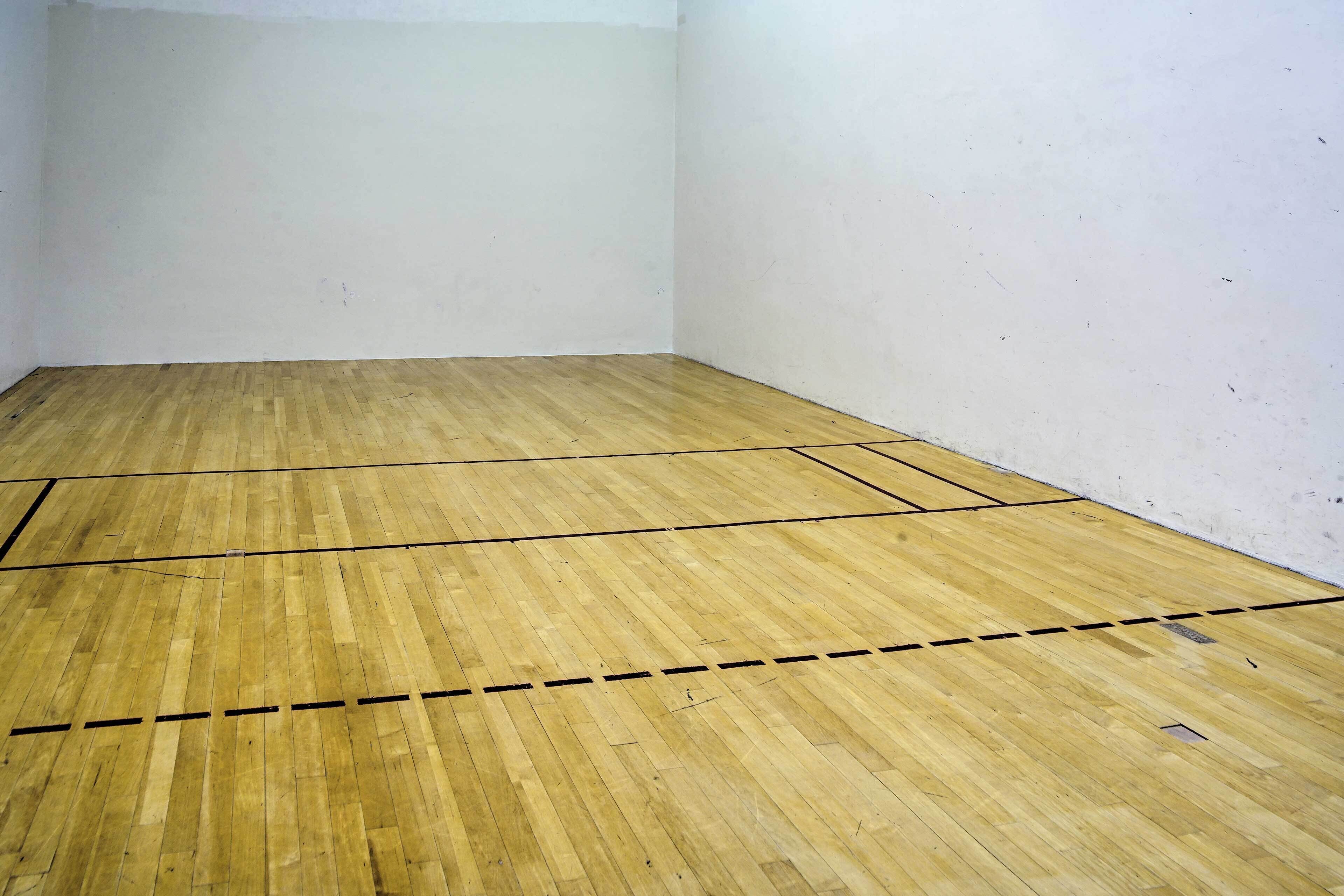 Squash-kenttä, jossa on puulattia ja valkoiset seinät.