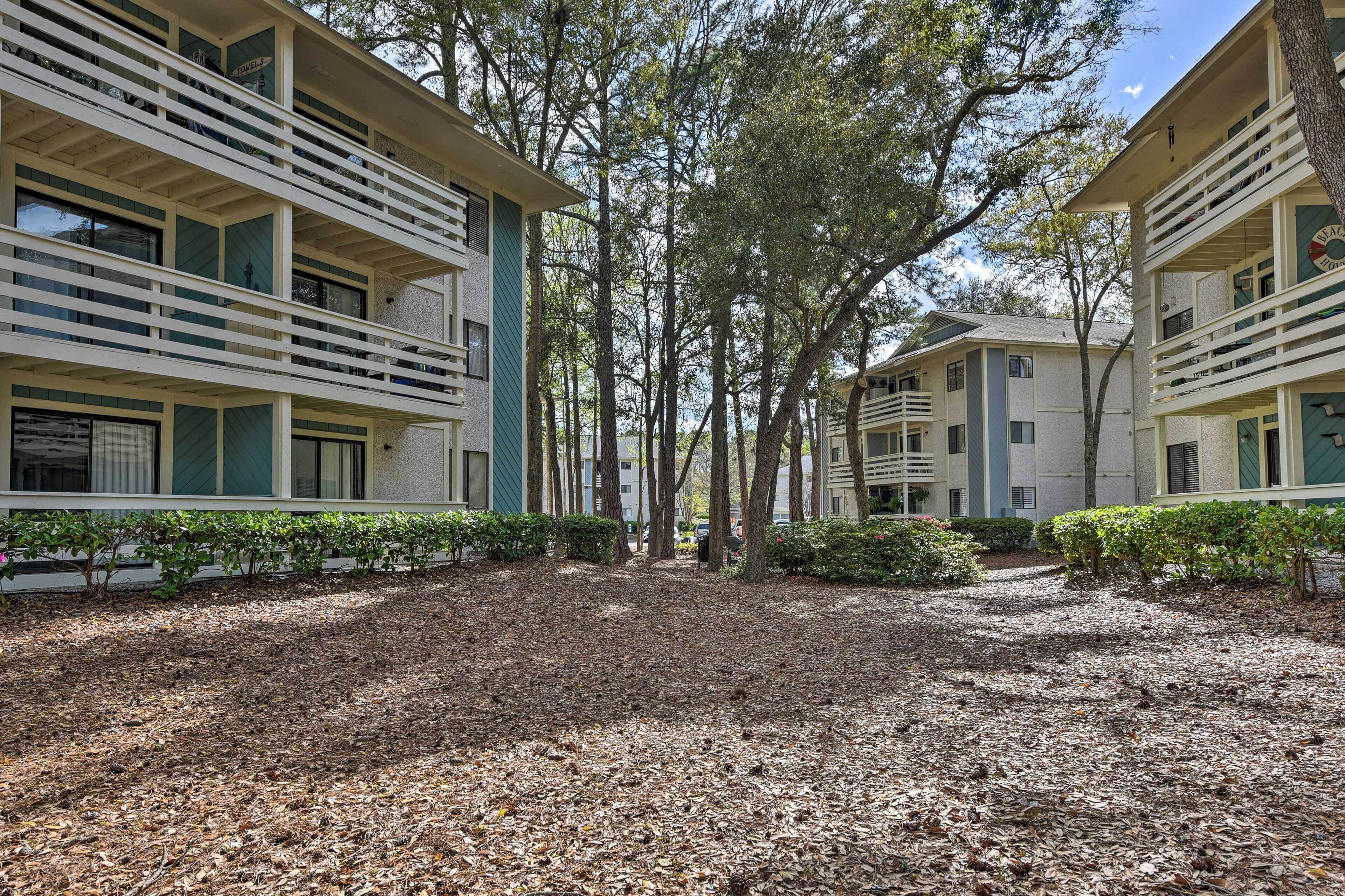 A courtyard with a gravel path, surrounded by buildings with balconies and large windows.