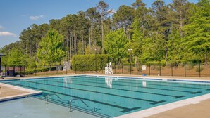 A rectangular swimming pool with clear blue water, surrounded by a black metal fence and a hedge. - Sunny Apex Vacation Rental w/ Pool Access! (Apex)