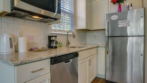 A kitchen with a stainless steel refrigerator, a dishwasher, a coffee maker, and a window with blinds. - Sunny Apex Vacation Rental w/ Pool Access! (Apex)