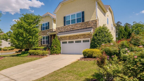 A two-story house with a garage, surrounded by well-maintained lawns and trees. - Sunny Apex Vacation Rental w/ Pool Access! (Apex)