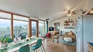 A spacious living area with a large dining table, chairs, and a view of the cityscape through large windows. - El Prado Duplex w/ Deck + Grill - 4 Mi to Town! (Taos)