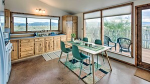 A kitchen with wooden cabinets, a dining table with chairs, and large windows offering a view of the mountains. - El Prado Duplex w/ Deck + Grill - 4 Mi to Town! (Taos)