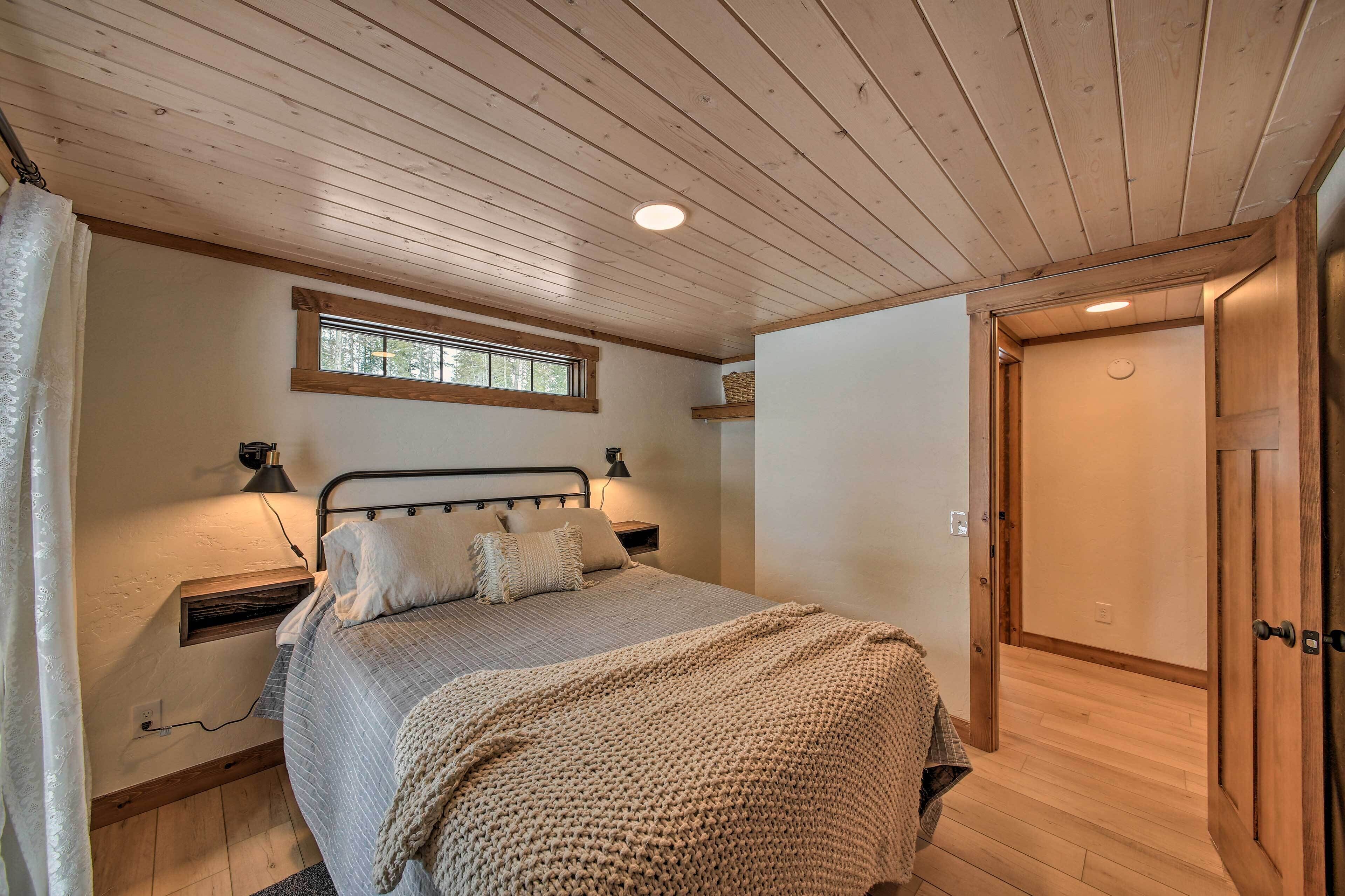 A bedroom with a bed, bedside tables, a window, and a door.