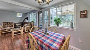 A cozy room with a wooden sofa, a dining table with a plaid tablecloth, and a chandelier. - Cloudcroft Cabin w/ National Forest Views! (Cloudcroft)
