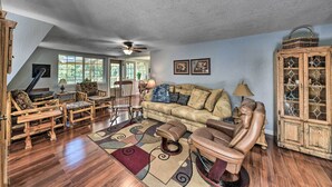 A cozy living room with a wooden floor, a ceiling fan, a sofa, a leather armchair, and a cabinet with glass doors. - Cloudcroft Cabin w/ National Forest Views! (Cloudcroft)