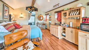 Un dormitorio acogedor con una cama grande, un aparador de madera y una zona de cocina con microondas.