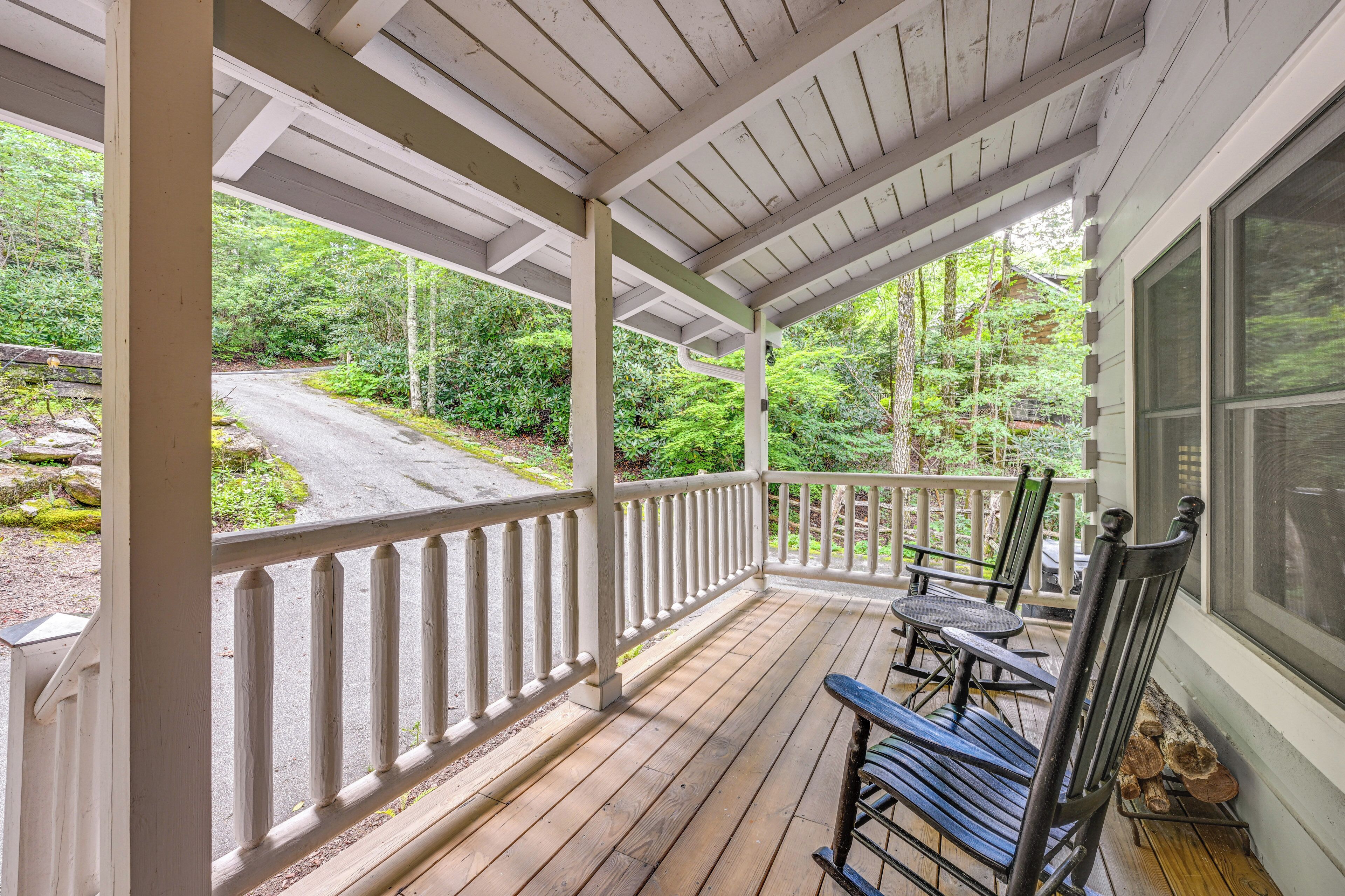 A wooden porch with a railing, a bench, and a table.