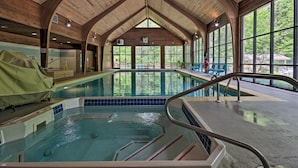 An indoor swimming pool with wooden beams and large windows.