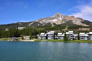 A lakeside resort with modern buildings, a mountain backdrop, and a clear sky. - Prismatic Mountain Studio < 1 Mi to Big Sky Resort (Big Sky)