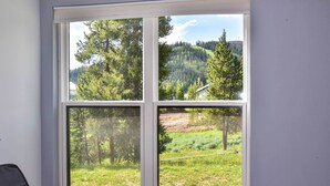 Una ventana que muestra un paisaje boscoso a través de cuatro vidrios.