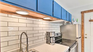 Una cocina con un lavamanos de acero inoxidable, una cafetera y una estufa.