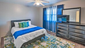 A bedroom with a bed, a dresser, a ceiling fan, a television, and a window with curtains. - Family-friendly Rockford Home w/ Private Yard! (Rockford)