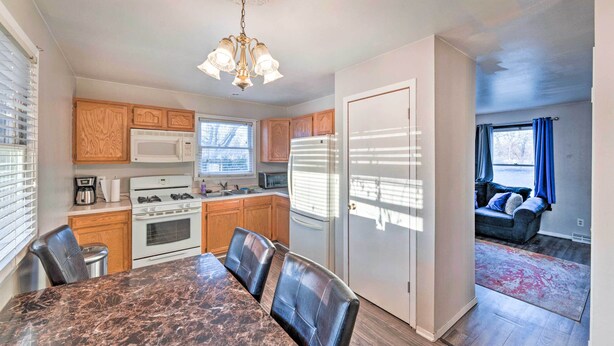 A modern kitchen with wooden cabinets, a marble countertop, and a dining area with a table and chairs. - Family-friendly Rockford Home w/ Private Yard! (Rockford)