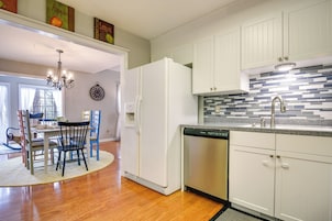 Una cocina con armarios blancos, refrigerador, lavavajillas y salpicadero de azulejos.