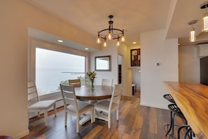 A dining area with a round wooden table, white chairs, and a chandelier. - Chic Port Angeles Home w/ Oceanfront Balcony! (Port Angeles)