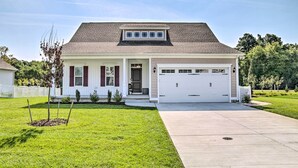 Une maison de plain-pied avec un garage à l’avant, un petit porche et une pelouse bien entretenue.