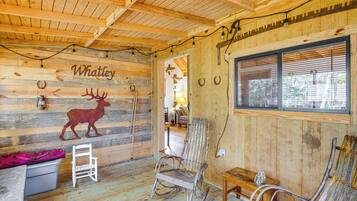 A rustic wooden interior with a deer mural, a rocking chair, and a bench.