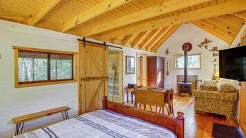 A cozy cabin with a wooden interior, a bed, a dining area, and a fireplace.