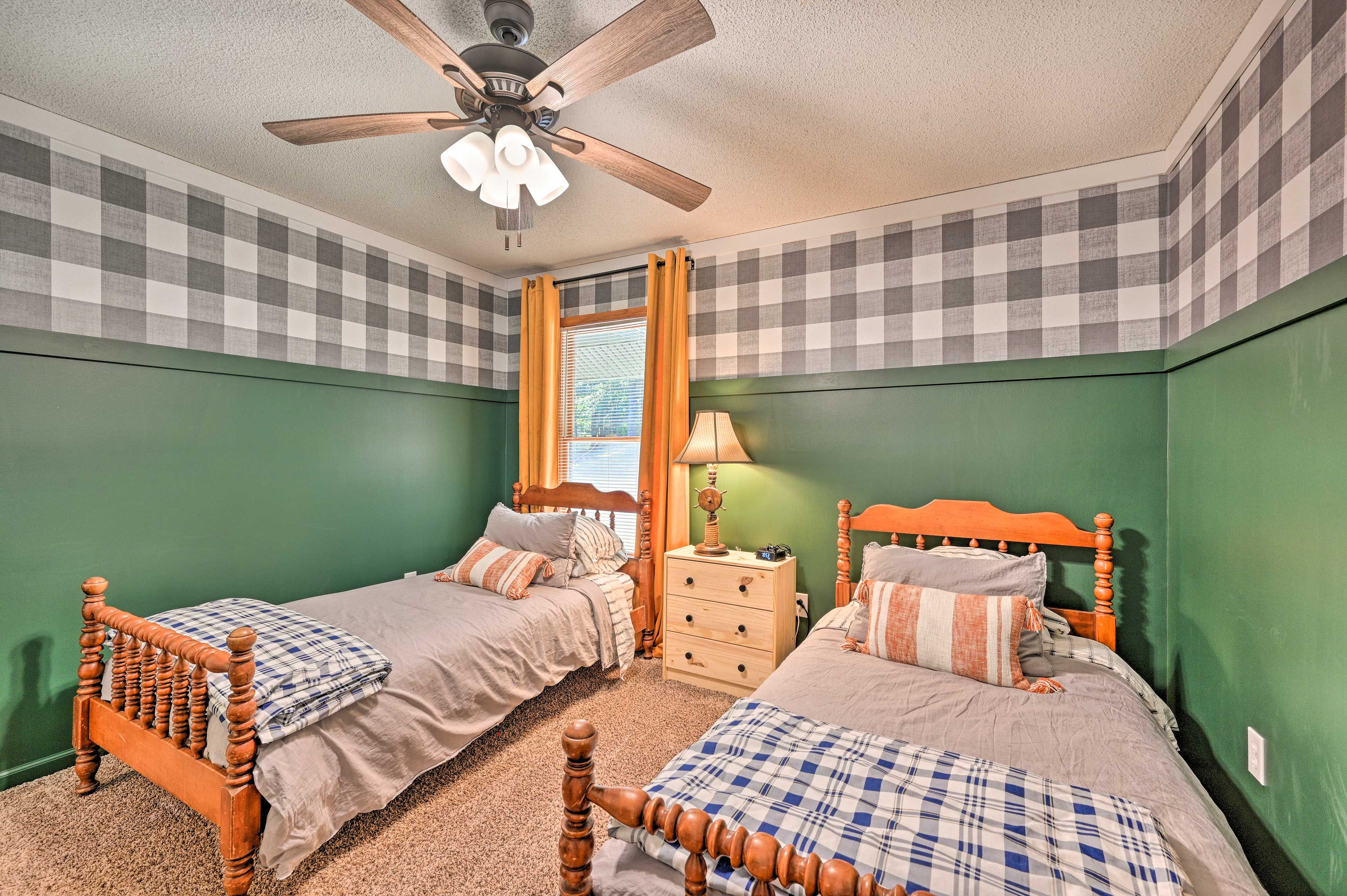 A bedroom with two wooden beds, a ceiling fan, and a window with curtains.