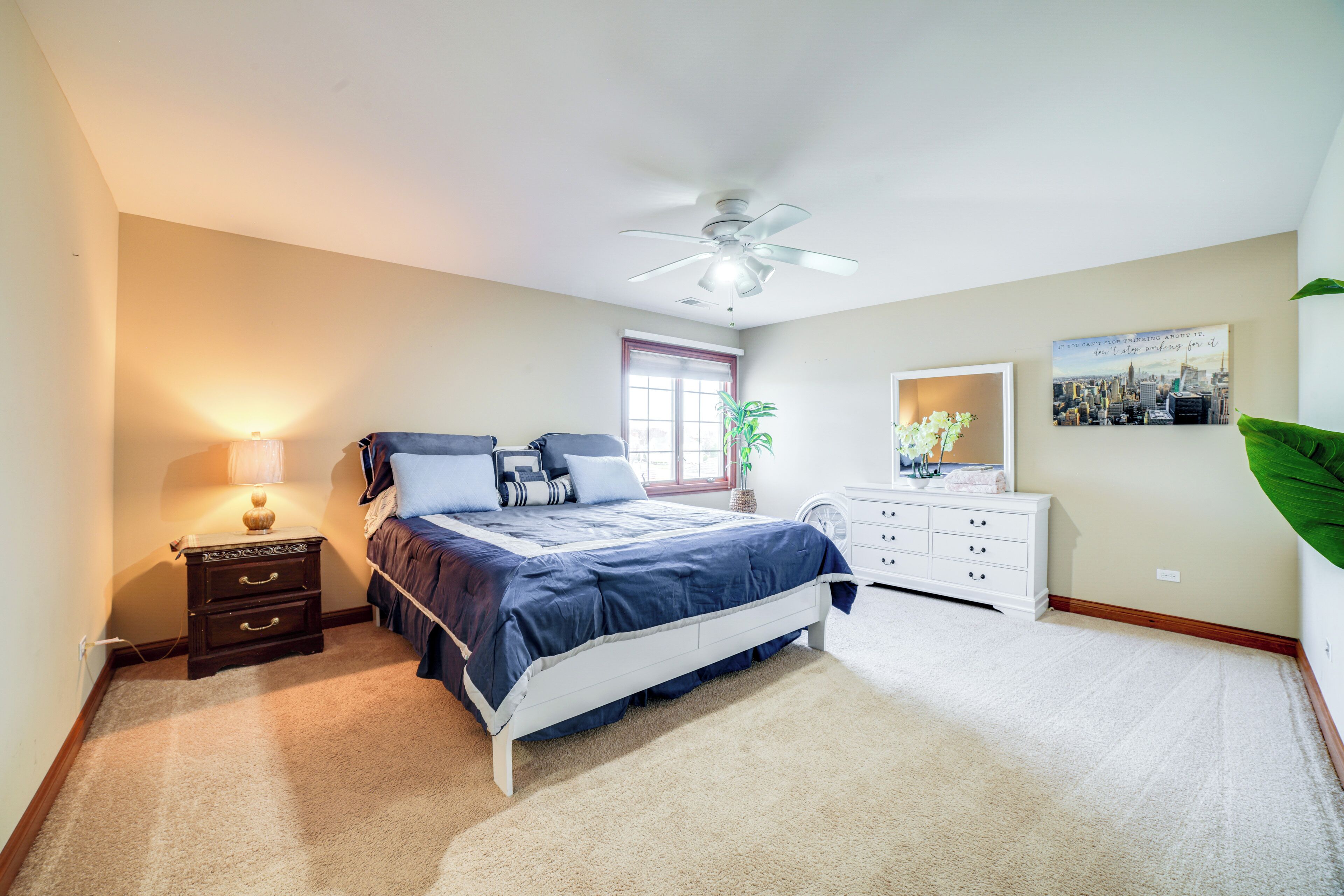 A bedroom with a bed, nightstand, dresser, and a ceiling fan.